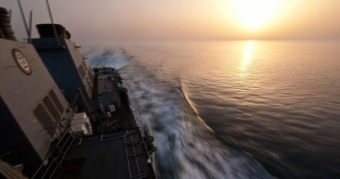 אוניית מכולות בקיבולת של 7,000 TEU הותקפה ועלתה באש, מה שהוביל לסבב תקיפות הדדיות בין ארה״ב לאיראן. תנועת מכליות הנפט במצר צנחה בחצי, ואנליסטים מזהירים: ״אם חברות הספנות יתייאשו ויפנו מערבה, שוק התובלה העולמי יחווה זעזוע״